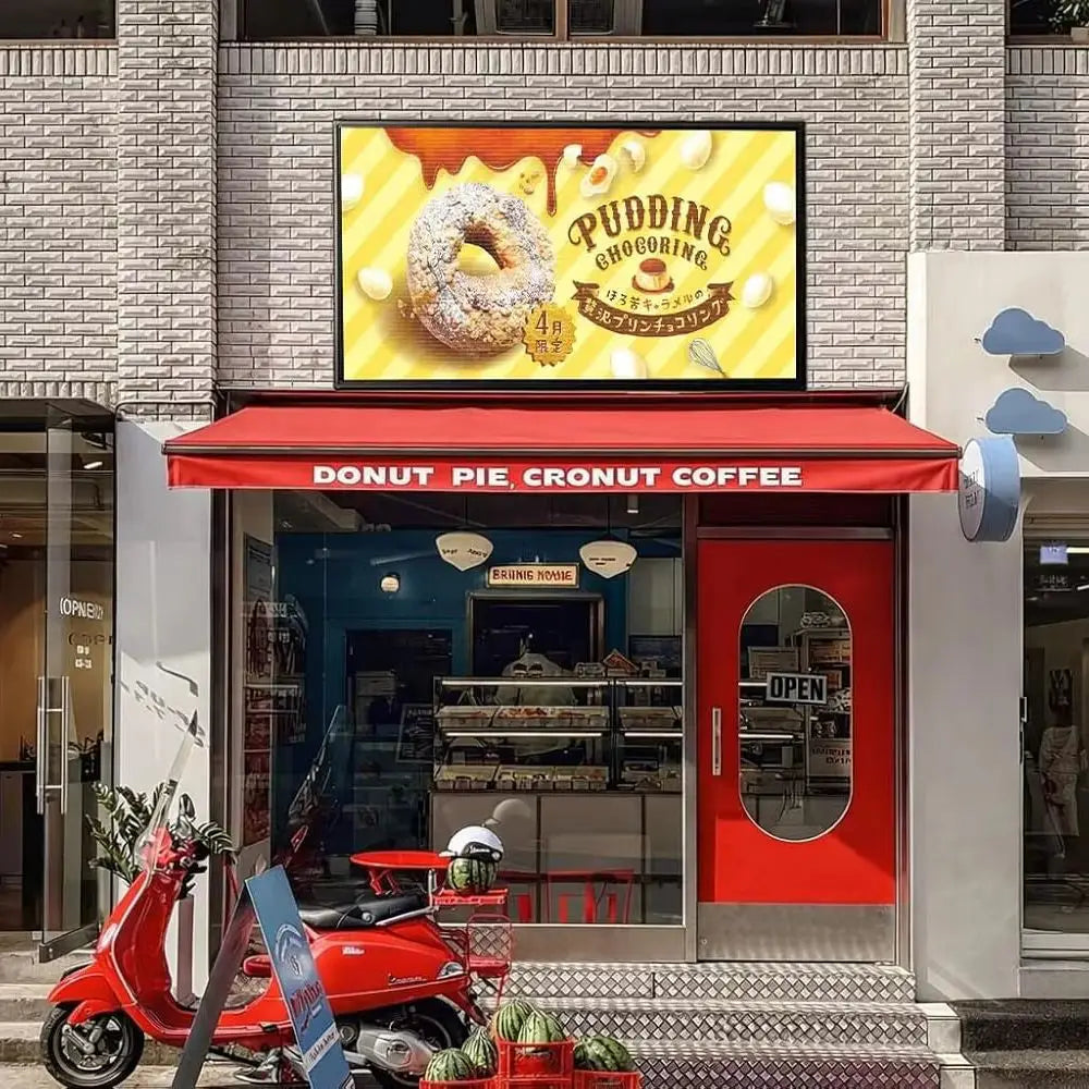 A P5 programmable LED display mounted above a bakery store entrance, showing a pudding donut advertisement.