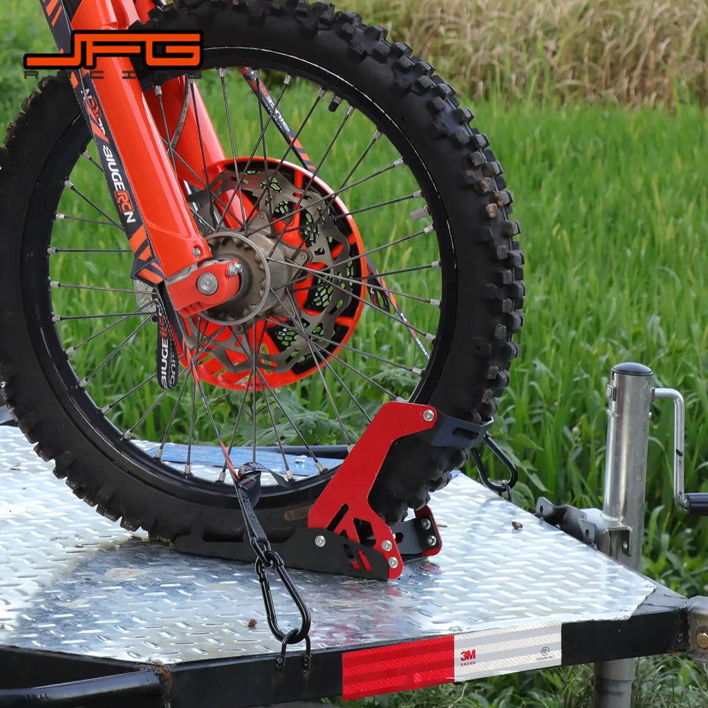 A dirt bike front wheel secured in a black and red motorcycle wheel chock on a trailer.