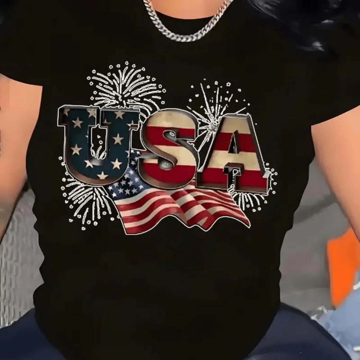 A black t-shirt with a metallic USA text design and American flag graphics