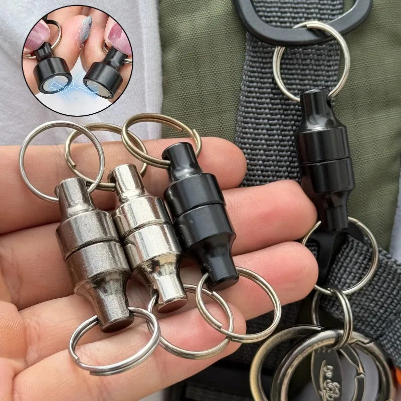 Hand holding several magnetic keychains in different metallic colors attached to a bag strap.