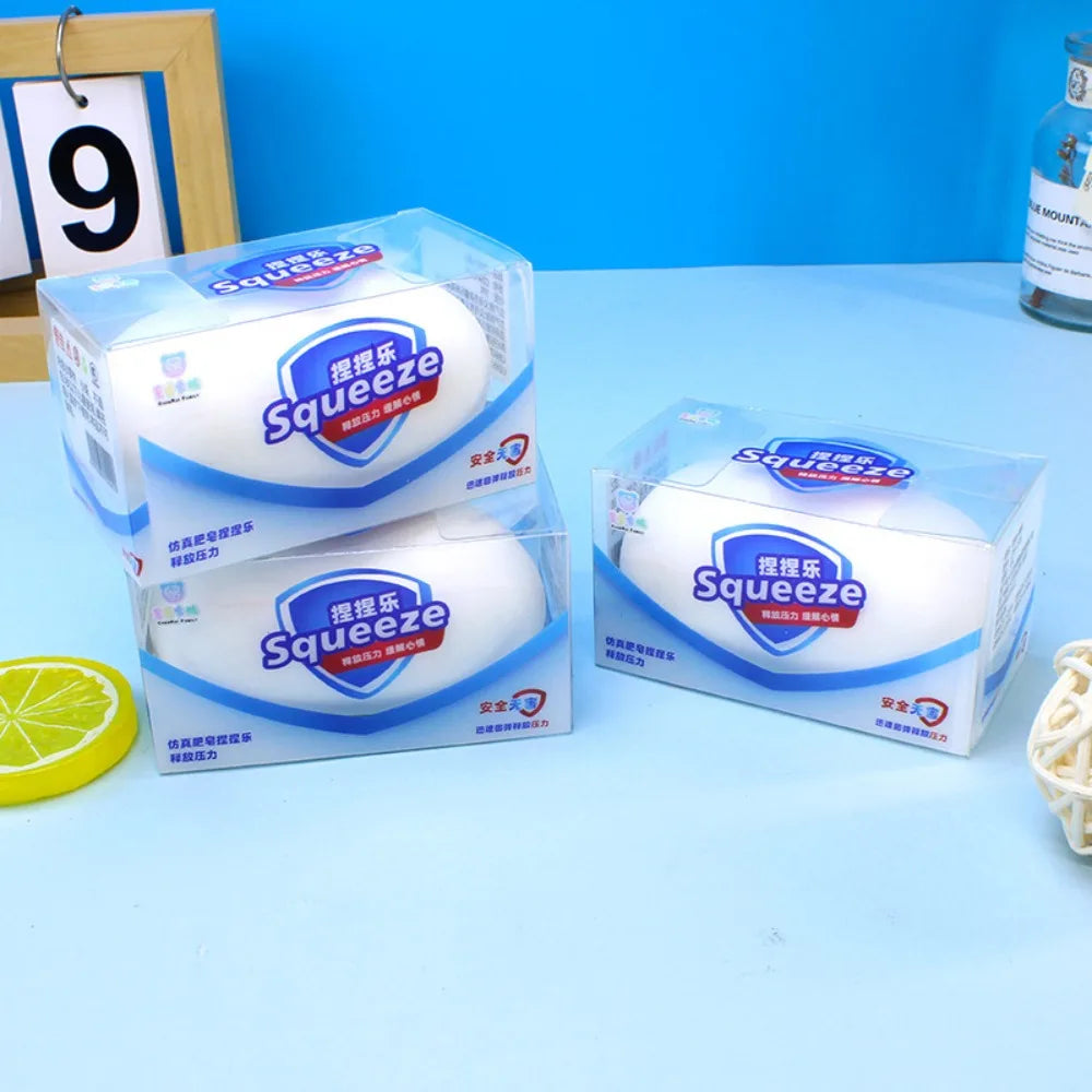 Three boxes of white soap-shaped stress relief squishy toys arranged on a blue surface