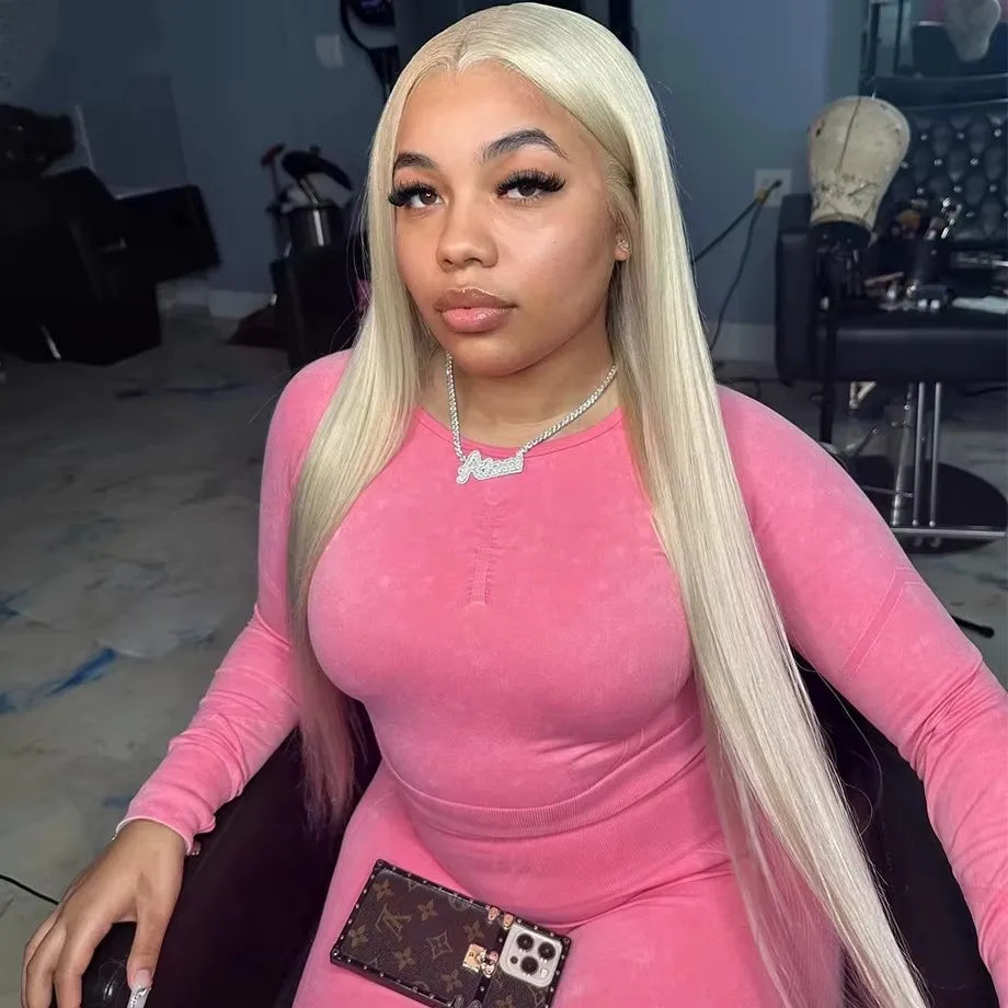 Long straight platinum blonde lace front human hair wig on a woman in a pink outfit