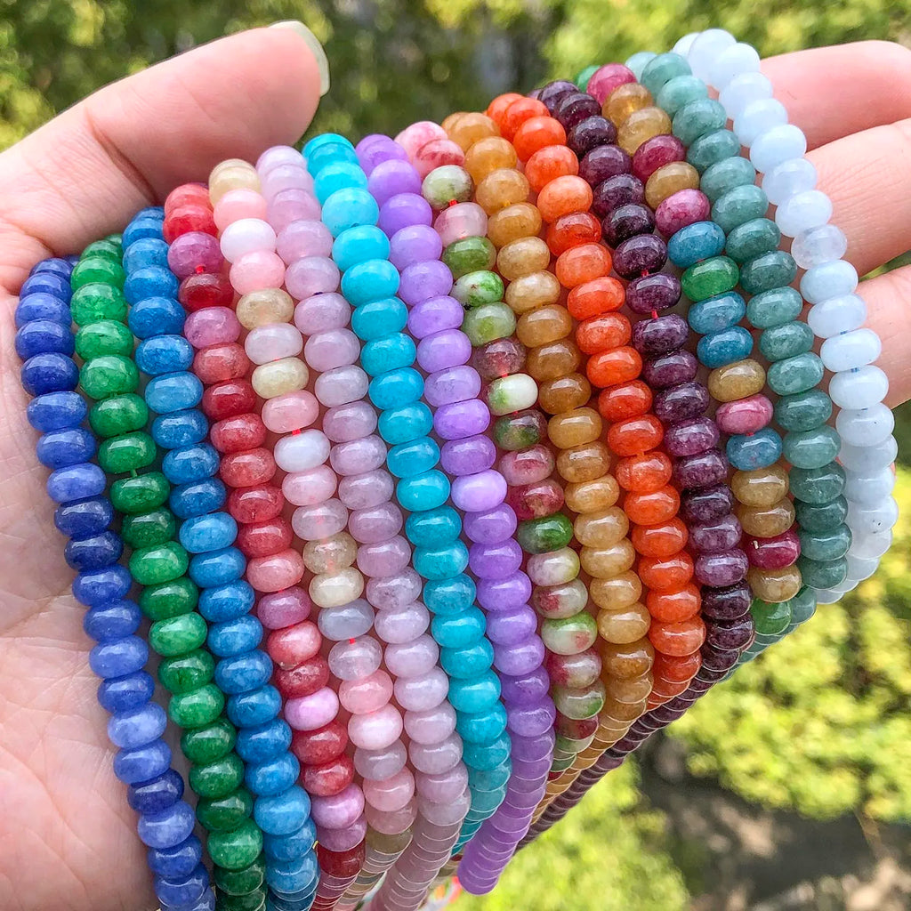 Close up of hand holding assorted colorful gemstone beads in outdoors setting