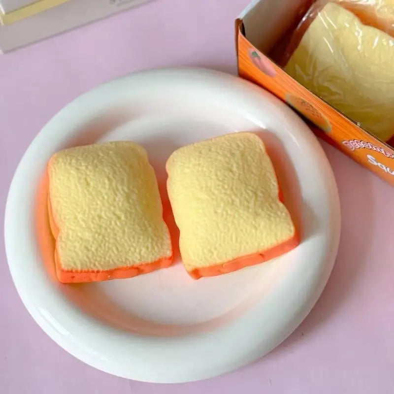 Two yellow toast squishy toys on a white plate with packaging