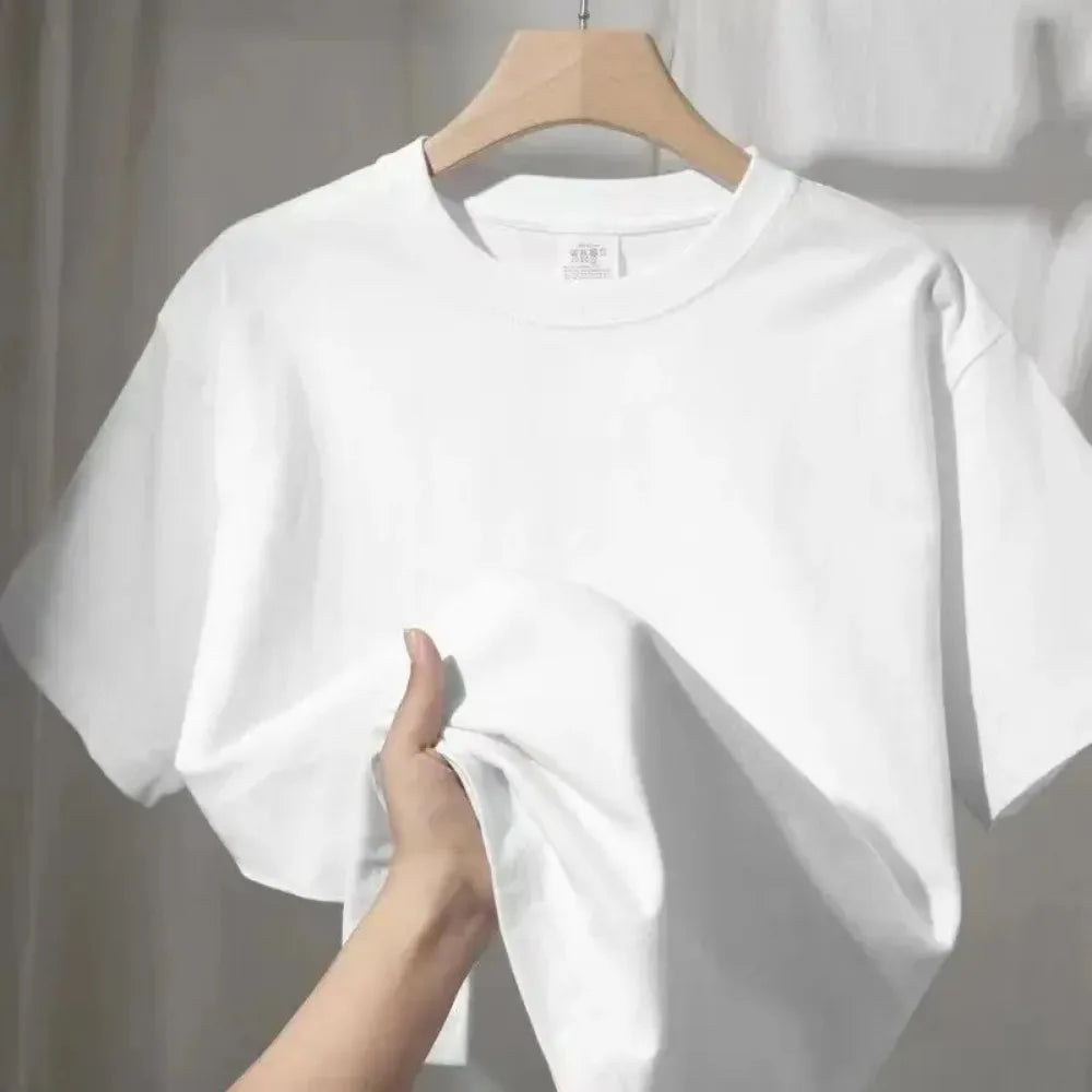 Close up of a hand holding up a white cotton t-shirt fabric