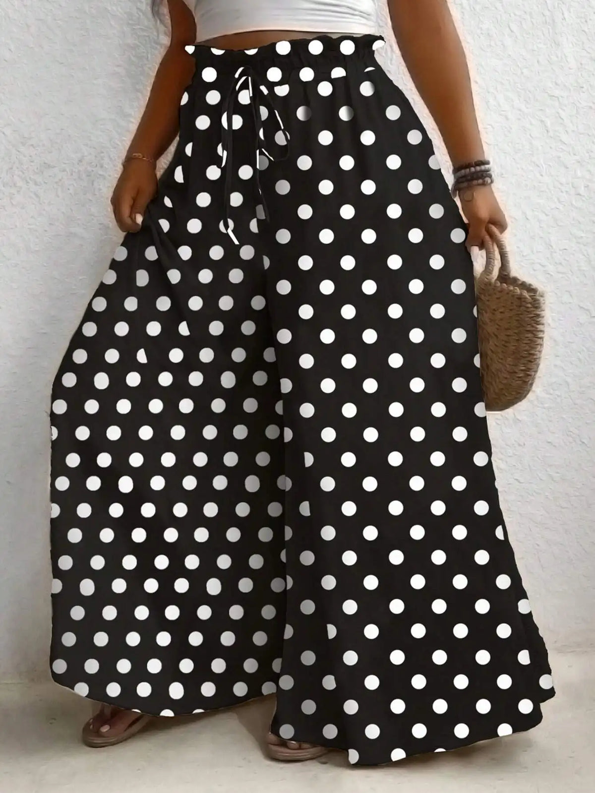 High waisted polka dot print wide leg pants with an elastic drawstring waist in black and white.