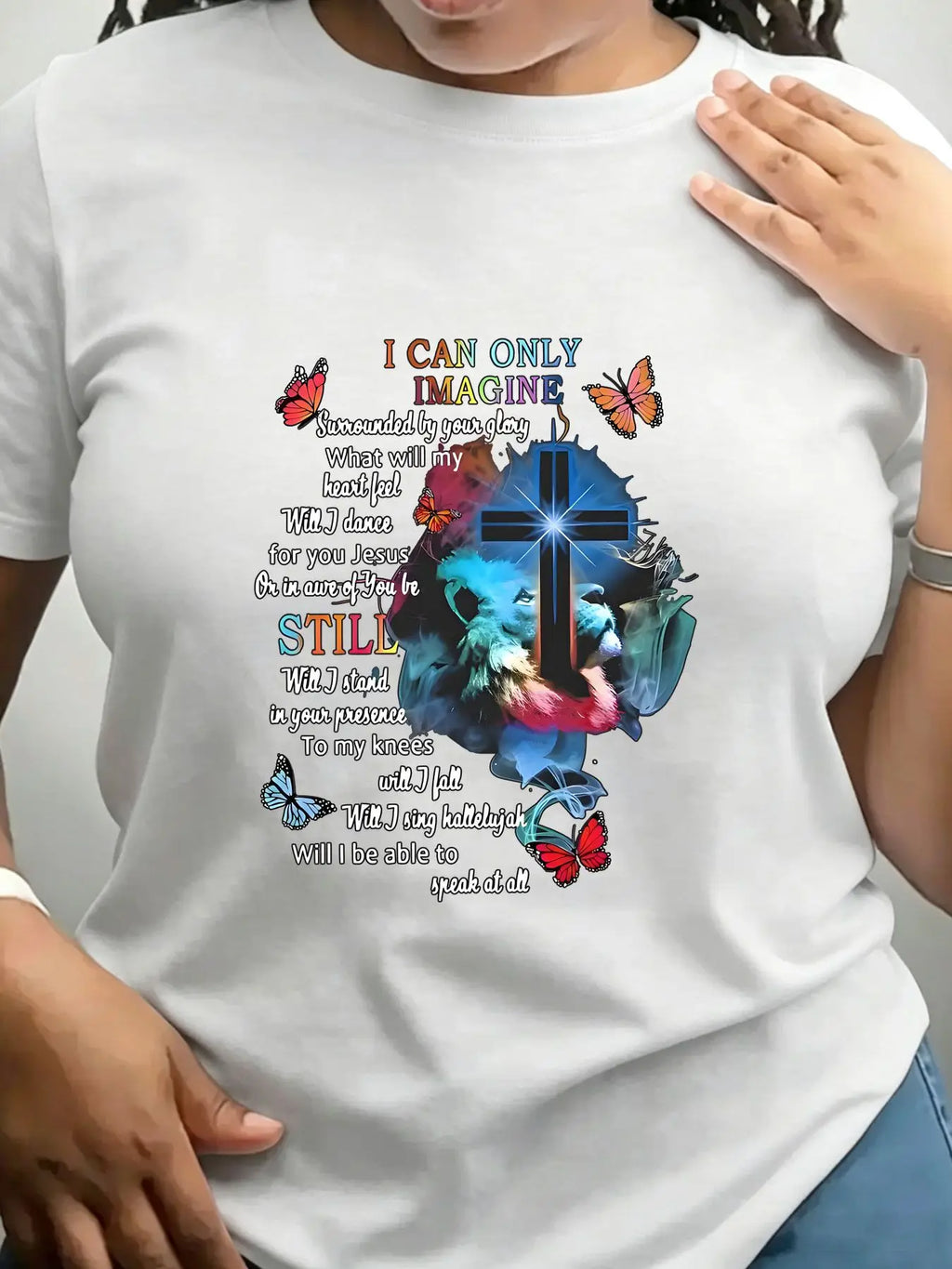 A white short-sleeved crew neck t-shirt with a religious graphic print featuring a cross, lion, butterflies, and lyrics