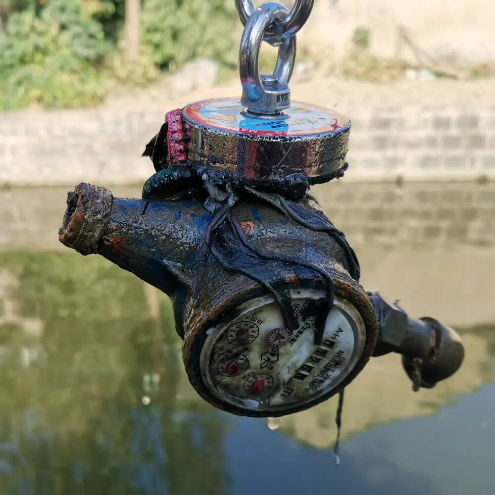 Fishing magnet lifting a rusted metal object from a body of water.