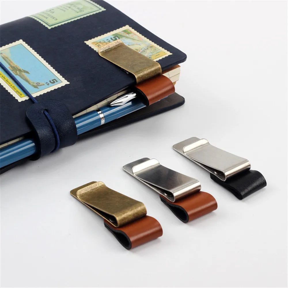 Metal and leather pen holder clips attached to a notebook, displayed on a white background.