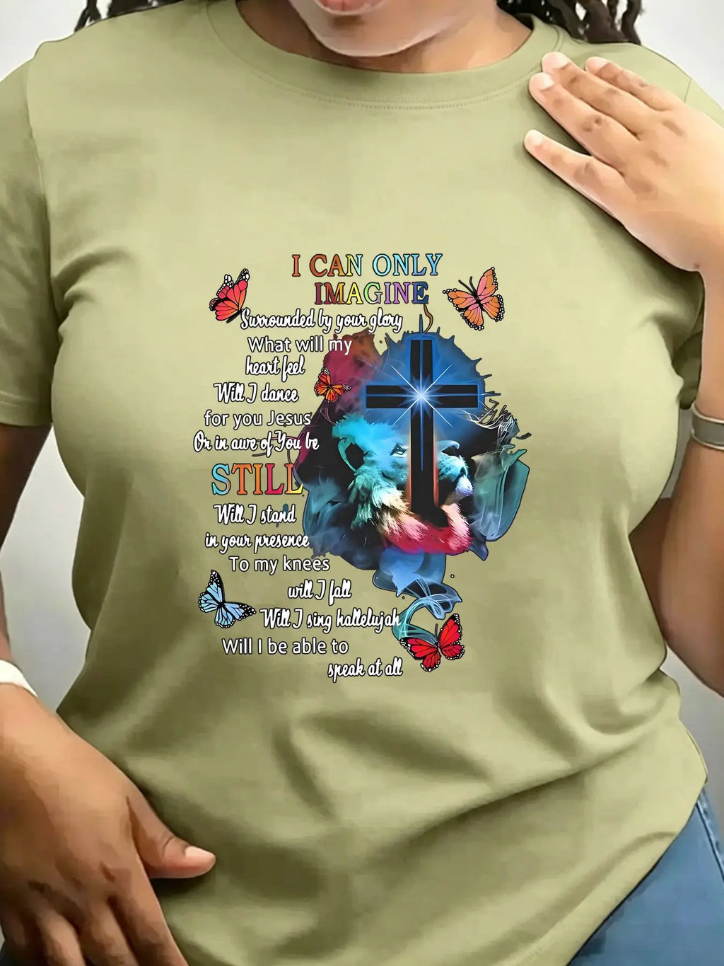 An olive green short-sleeved crew neck t-shirt with a religious graphic print featuring a cross, lion, butterflies, and
