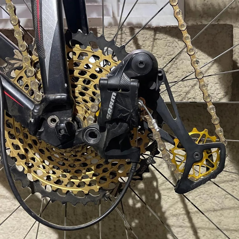 A gold jockey wheel installed on a mountain bike rear derailleur with a wide range cassette
