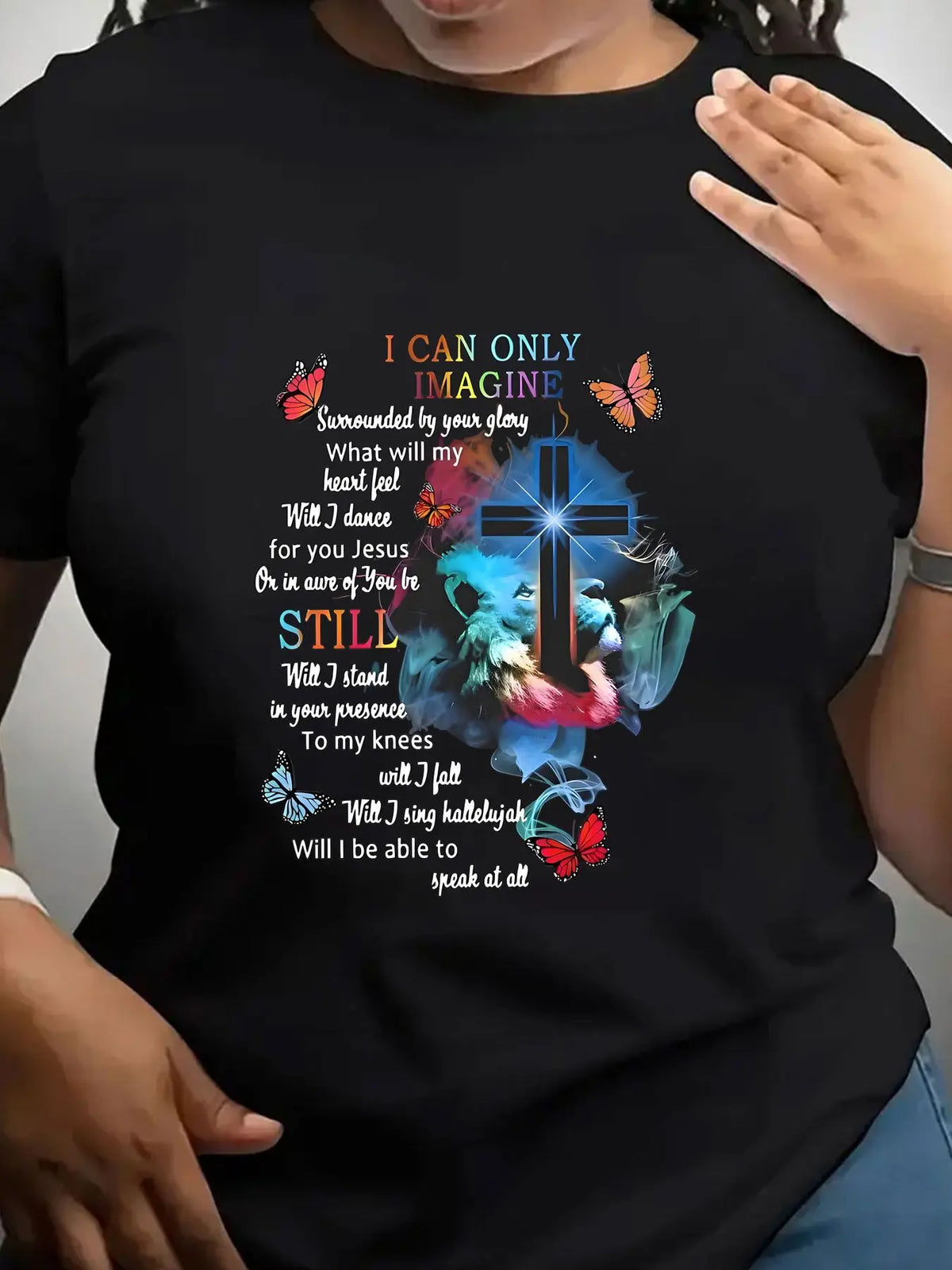 A black short-sleeved crew neck t-shirt with a religious graphic print featuring a cross, lion, butterflies, and lyrics