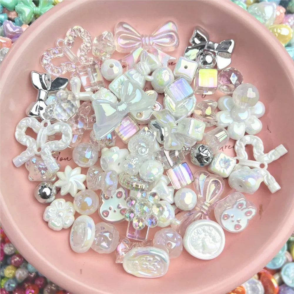A pink bowl containing a collection of white, clear, and iridescent craft beads in bow, flower, and animal shapes.