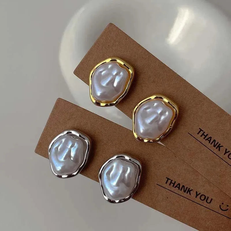 Irregular round pearl earrings with gold and silver metal rims displayed on cardboard backing cards