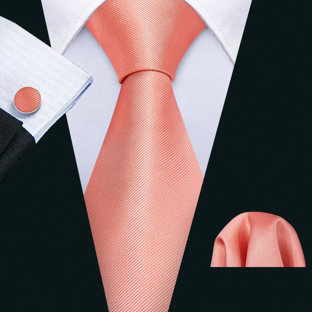 Coral pink solid tie, pocket square and cufflinks set on a shirt collar