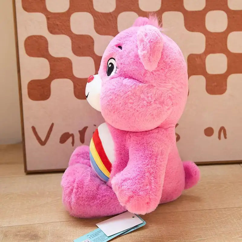 Side profile of a pink Care Bear plush toy with rainbow belly badge