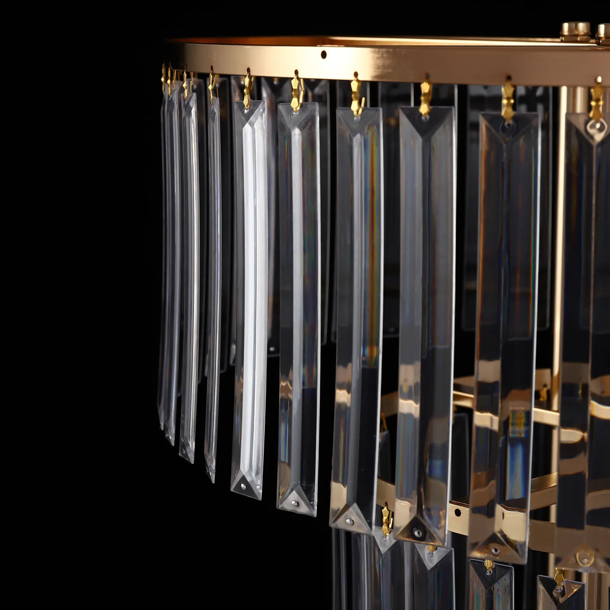 Close-up detail of the crystal prisms hanging from the tiered gold frame.