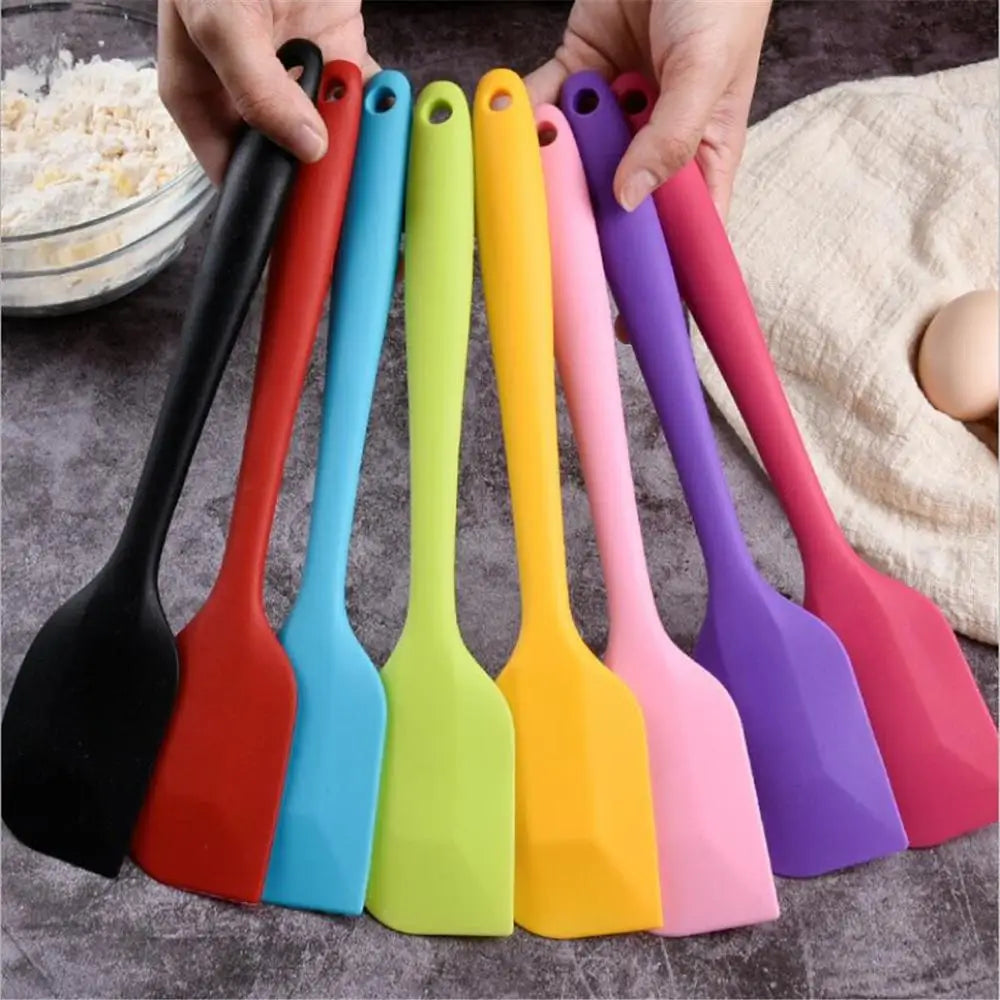 A collection of colorful silicone kitchen spatulas in various vibrant colors being held together.