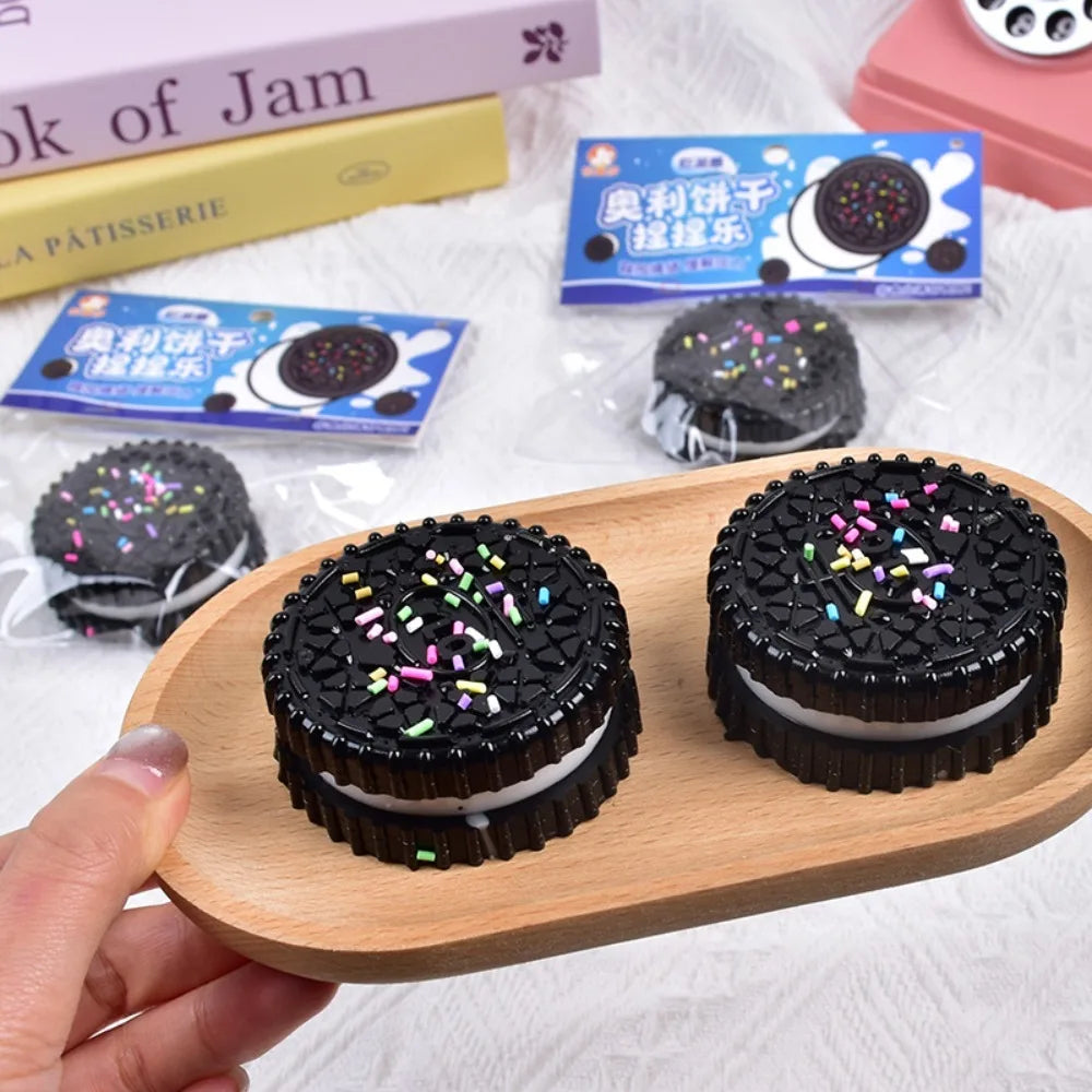 Two black and white cookie-shaped stress relief squishy toys on a small wooden tray.