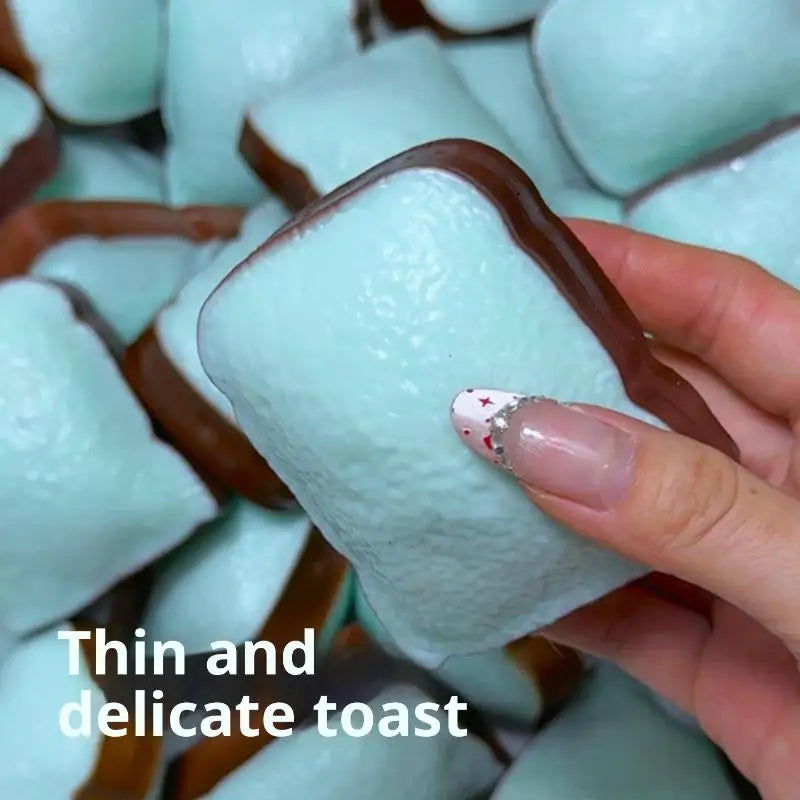 A hand holding a mint green and chocolate brown squishy bread toy