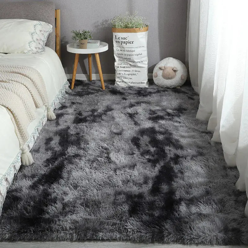 Grey and black tie-dye style plush area rug in a bedroom.