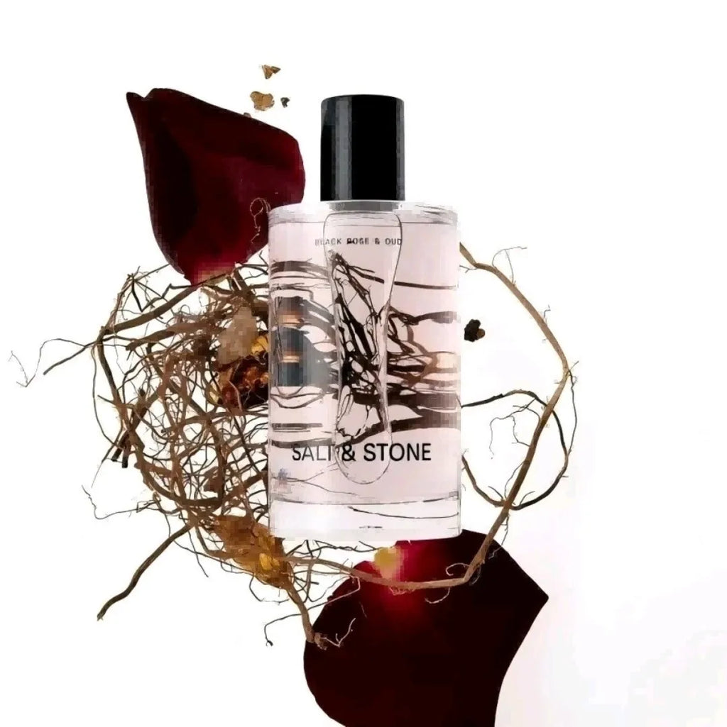 Body mist fragrance bottle surrounded by dried rose petals and roots