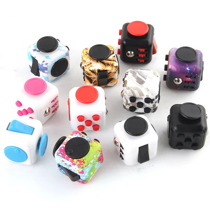 An assortment of multi-coloured fidget cubes scattered on a white background.