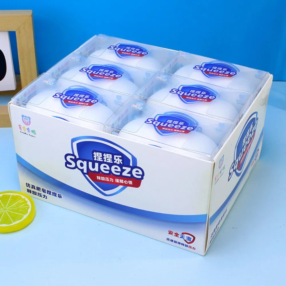 Bulk retail display box containing multiple white soap-shaped stress relief squishy toys