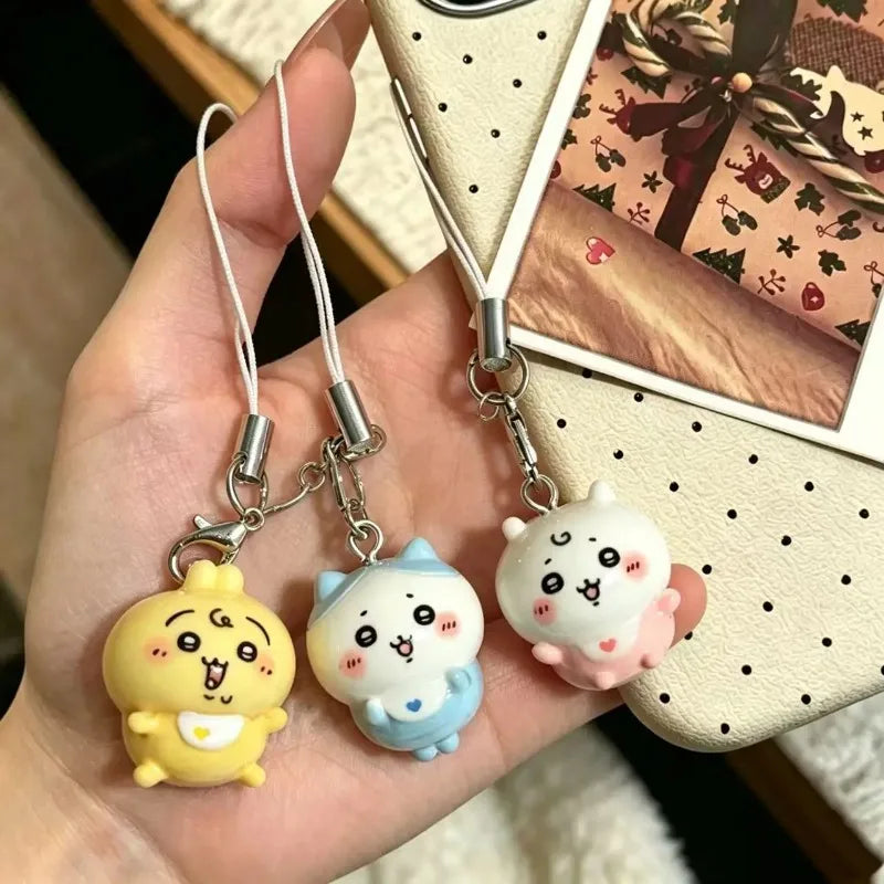 A hand holding three colorful resin character charms for phones and bags.
