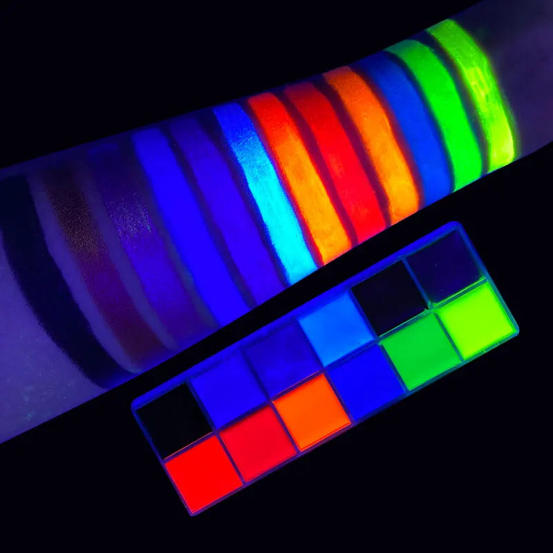 A 12-color glow-in-the-dark face and body paint palette with color swatches on an arm viewed under UV light