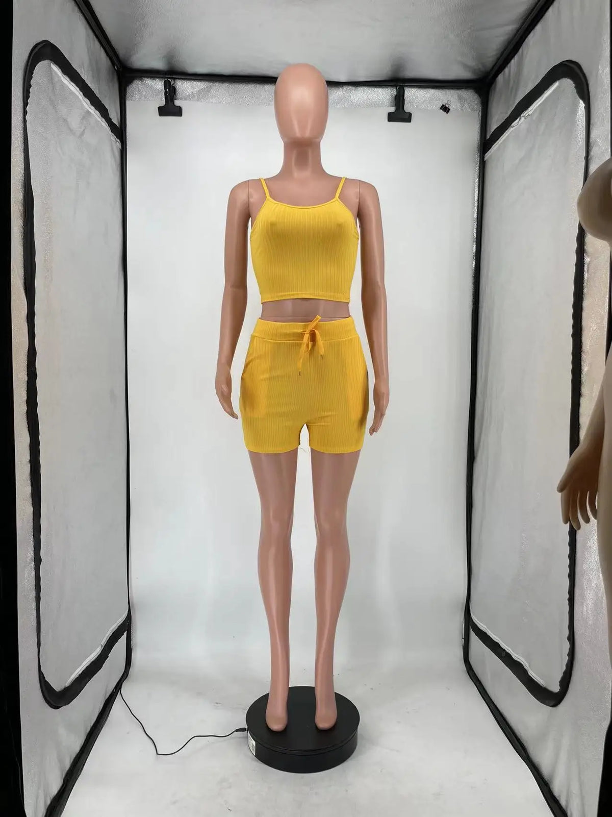 A yellow three-piece set of a ribbed tank top, drawstring shorts, and a long sleeveless cardigan displayed on a mannequin.