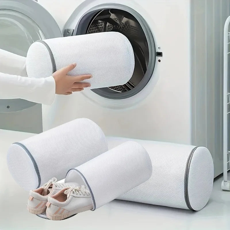 A white cylindrical mesh laundry bag for washing sneakers in a washing machine.