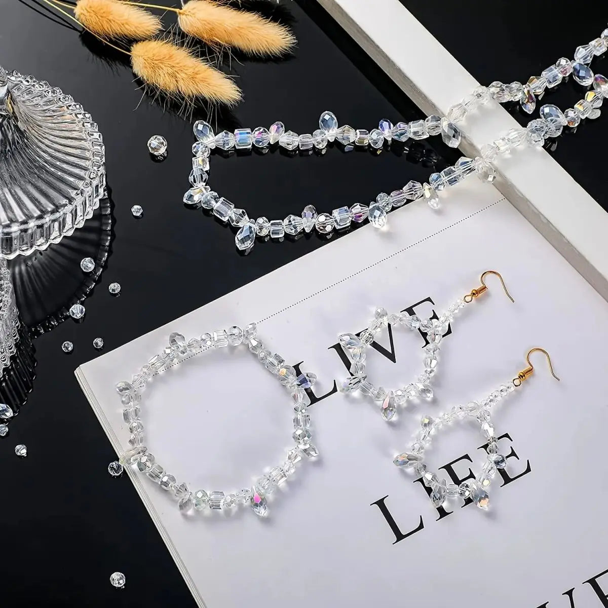 Handcrafted crystal bead jewelry including necklaces and earrings laid out on a white surface.