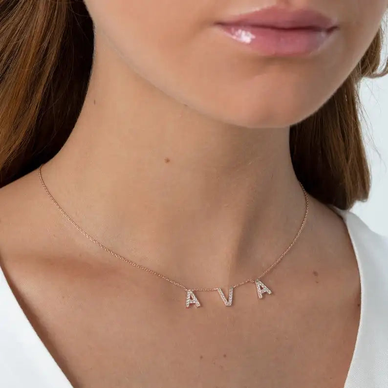Rose gold letter necklace with crystals worn on a woman's neck