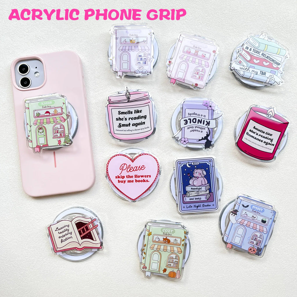 Collection of various acrylic book-themed phone grips featuring designs of bookstores, candles, and romantic quotes.