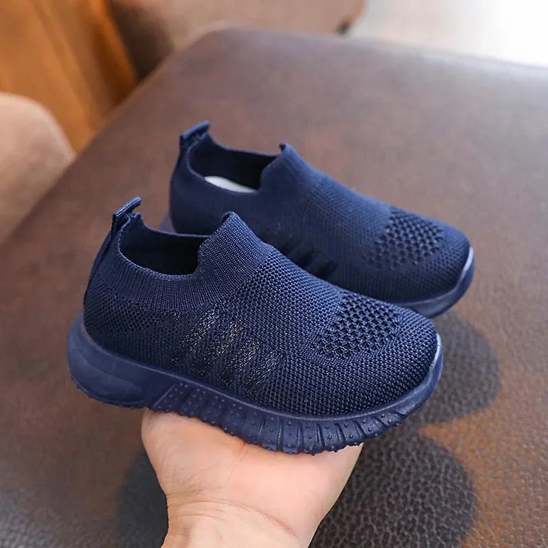 A single navy blue kids knitted slip-on sneaker held in a hand
