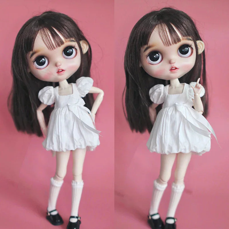 Blythe doll wearing a white dress and white lace trim knee-high socks with black shoes