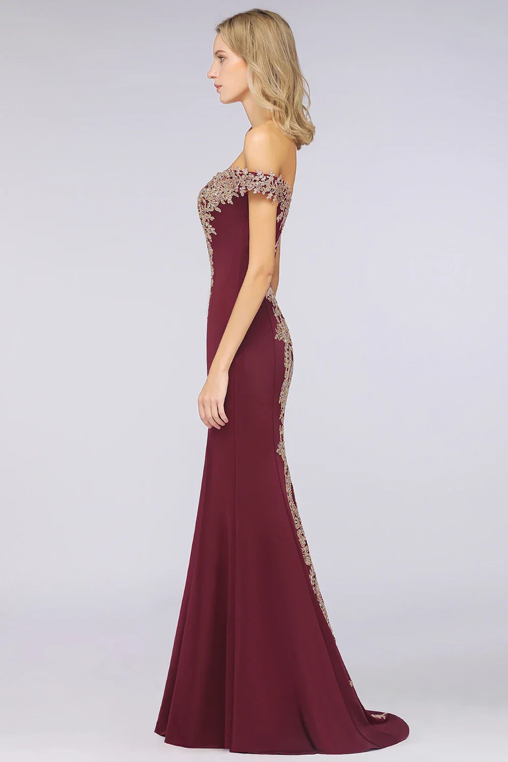 Side profile of a burgundy mermaid gown with gold lace embroidery