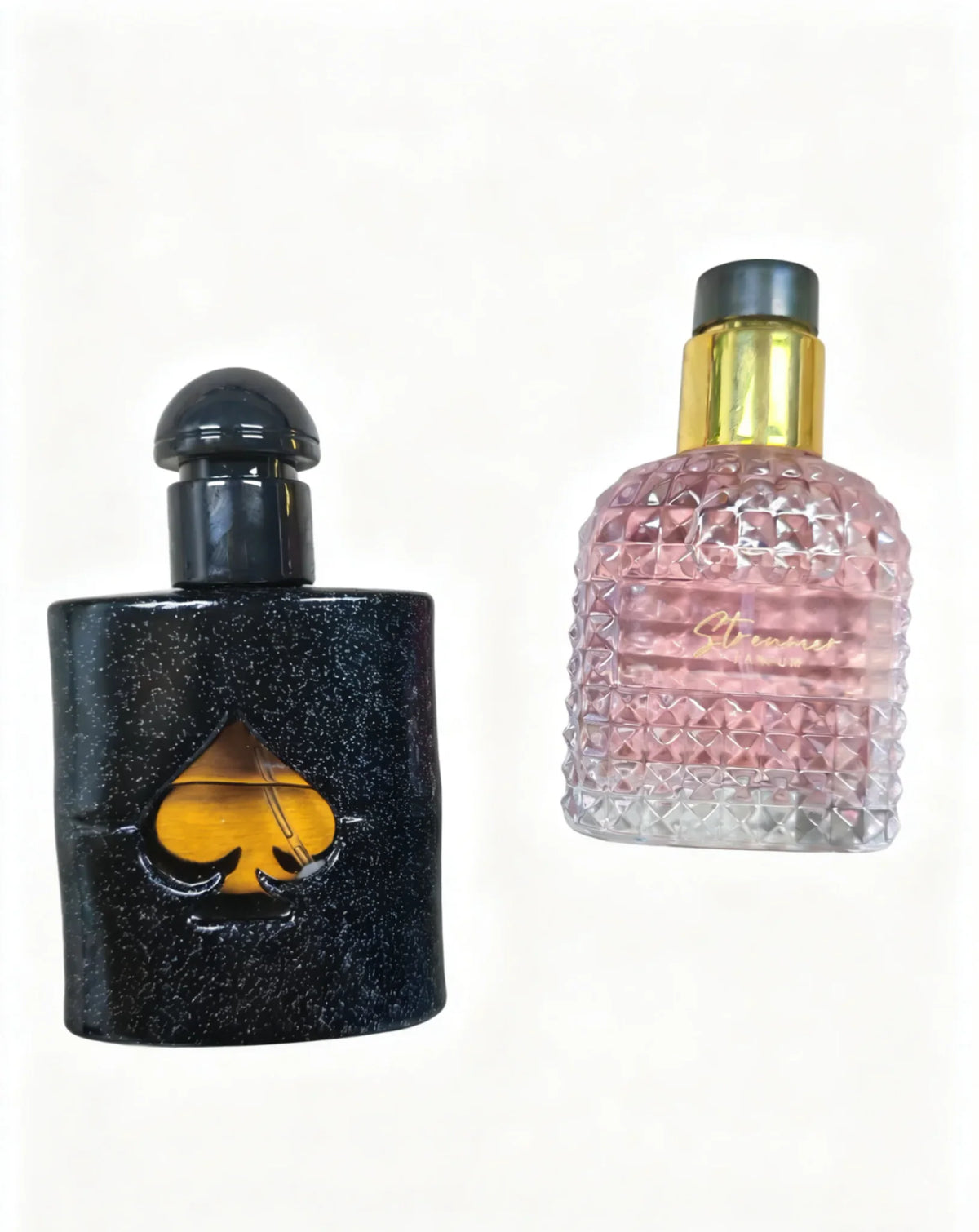 Two perfume bottles, one black bottle with a spade-shaped cutout and a textured pink bottle with a gold cap.