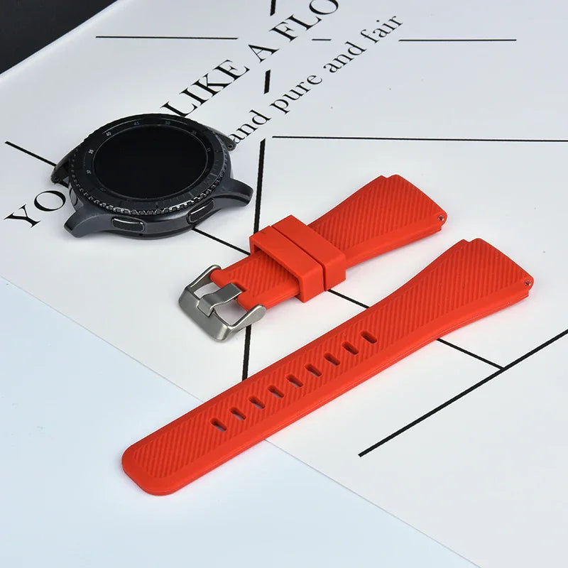A red silicone sport watch band displayed next to a black smartwatch face on a white surface.