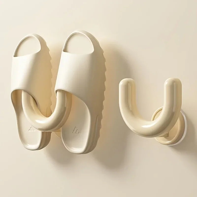A cream wall-mounted slipper rack holding a pair of cream sandals.