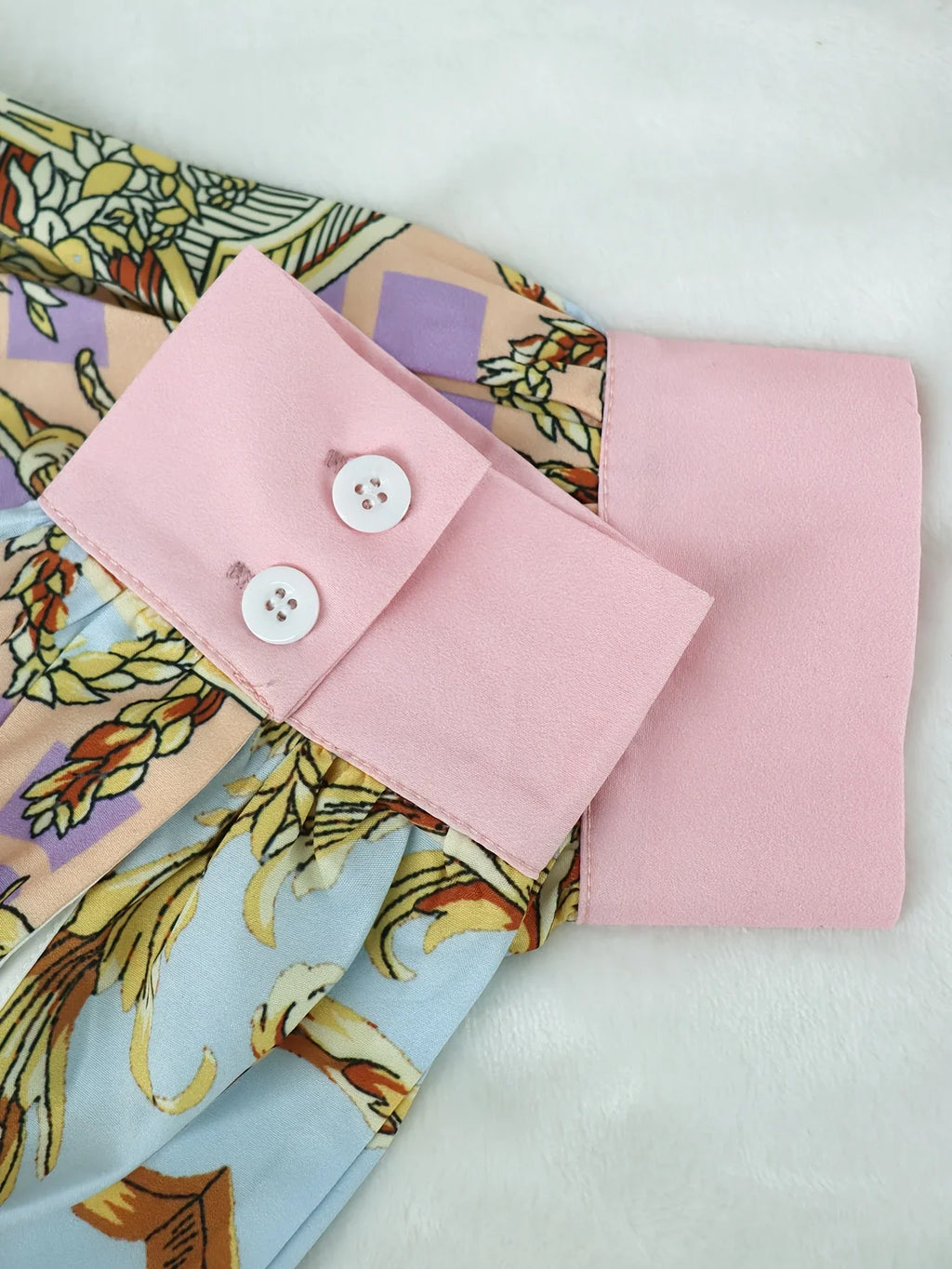 Close up of the pink buttoned cuffs on the sleeves of a women's patterned long sleeve shirt.