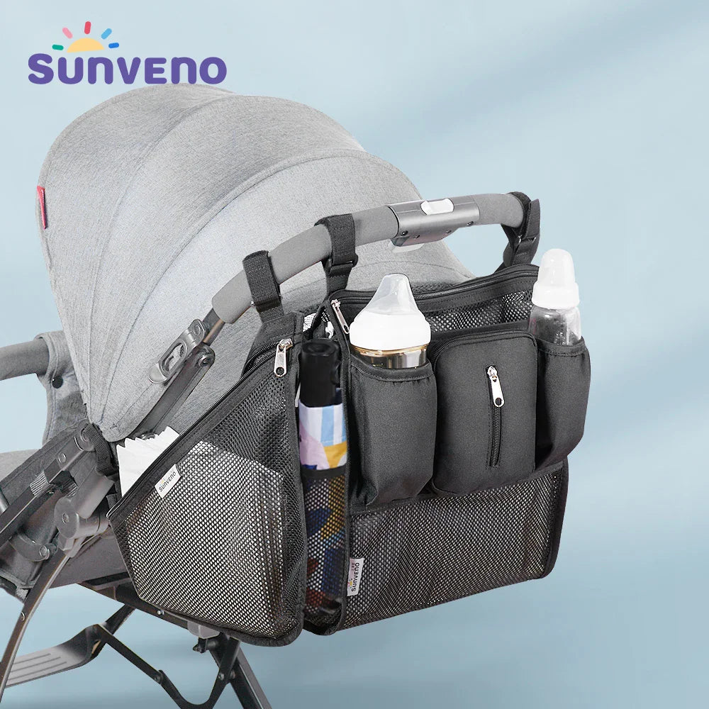 Black stroller organizer bag with multiple compartments and bottle holders attached to a grey baby stroller