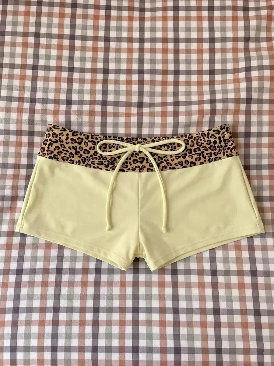 High waisted bikini bottoms featuring a leopard print waistband and pale yellow lower section with drawstring detail
