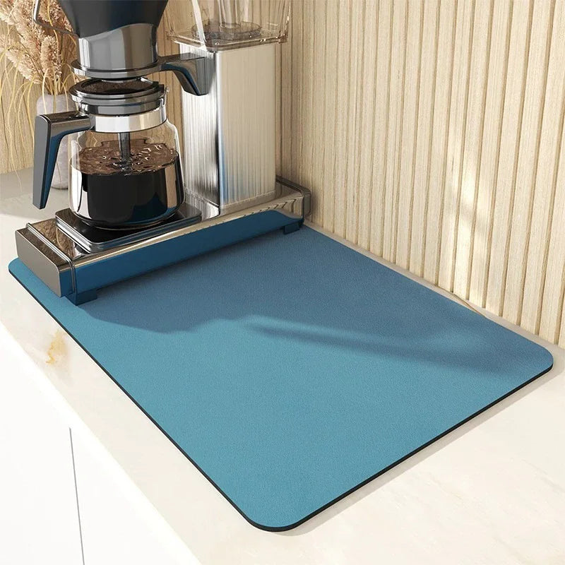 Blue absorbent kitchen drying mat under a coffee machine on a countertop.