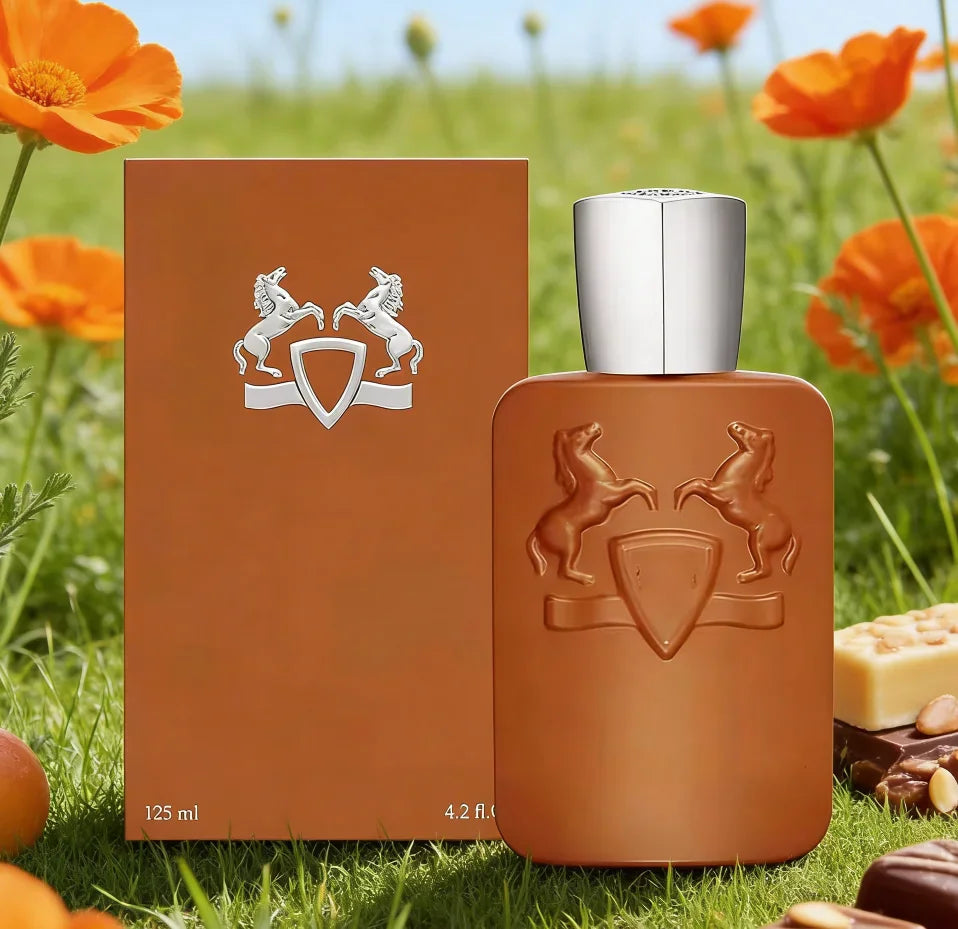 Brown perfume bottle with matching box in a grassy field with oranges and chocolates