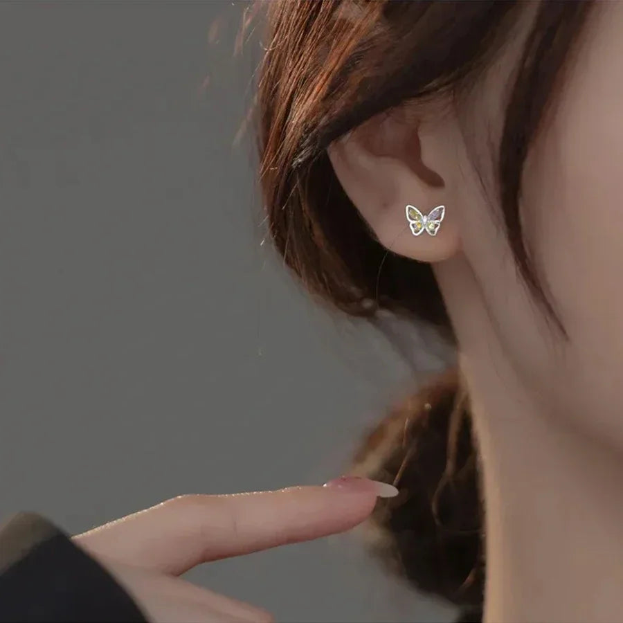 A woman wearing a small butterfly stud earring in her earlobe