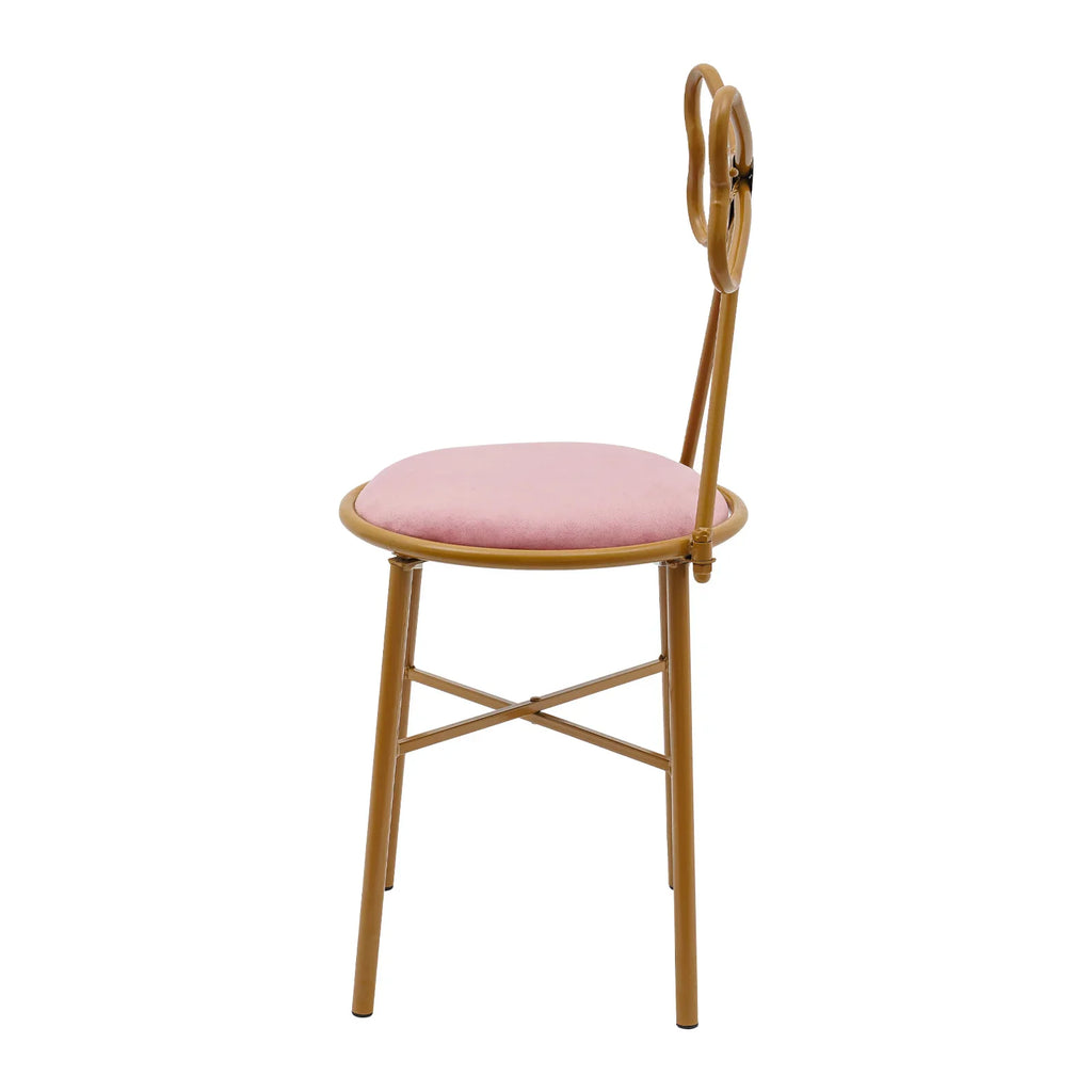 Side view of a pink velvet vanity chair with gold metal butterfly backrest and legs.