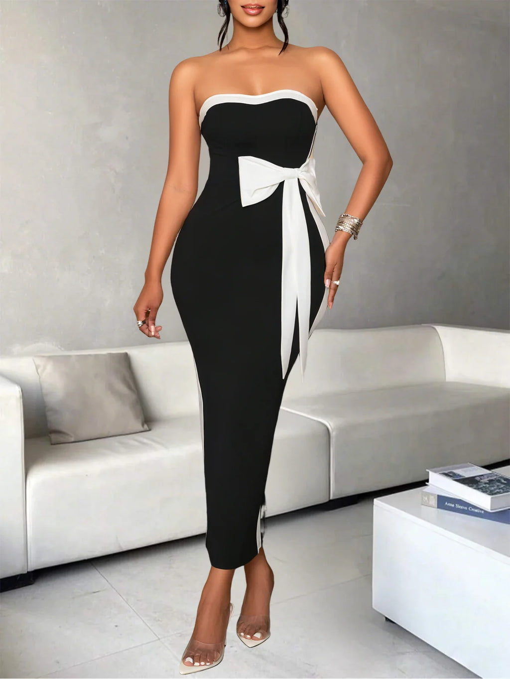 Woman wearing a black and white strapless midi dress with a large bow detail on the waist