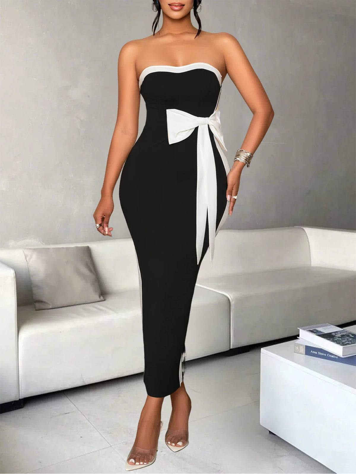 Woman wearing a black and white strapless midi dress with a large bow detail on the waist